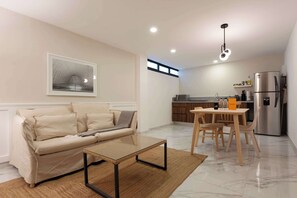 Un salon moderne avec un canapé, une table basse en verre et un coin repas comprenant une table et des chaises.
