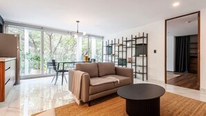 A modern living room with a sofa, a coffee table, and a dining area with a table and chairs. - w* | Enchanting 1BR w/ Terrace in Prime Polanco (Ciudad de México)