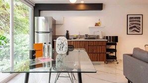 A modern kitchen with a glass dining table, a built-in oven, and a coffee machine. - w* | Enchanting 1BR w/ Terrace in Prime Polanco (Ciudad de México)