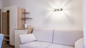 A modern living room with a sofa, a coffee machine, and a wooden cabinet. - Apartment "Isabel" with Mountain View, French Balcony & Wi-Fi (Bolzano)