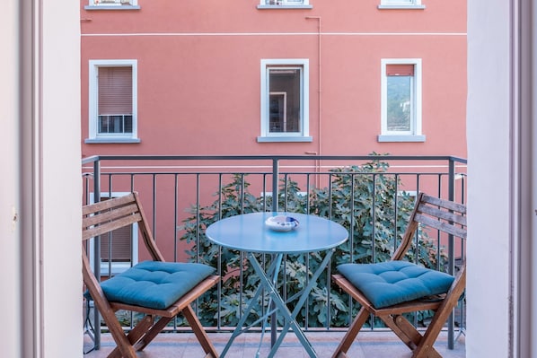 A balcony with two wooden chairs and a small round table.