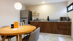 A modern kitchen with a round wooden table, grey chairs, a built-in oven, a microwave, and a hanging light fixture. - w* | Fascinating 1BR with Perfect Deco in Polanco (Ciudad de México)