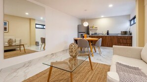 A modern living room with a glass coffee table, a sofa, and a dining area with chairs and a kitchen in the background. - w* | Fascinating 1BR with Perfect Deco in Polanco (Ciudad de México)
