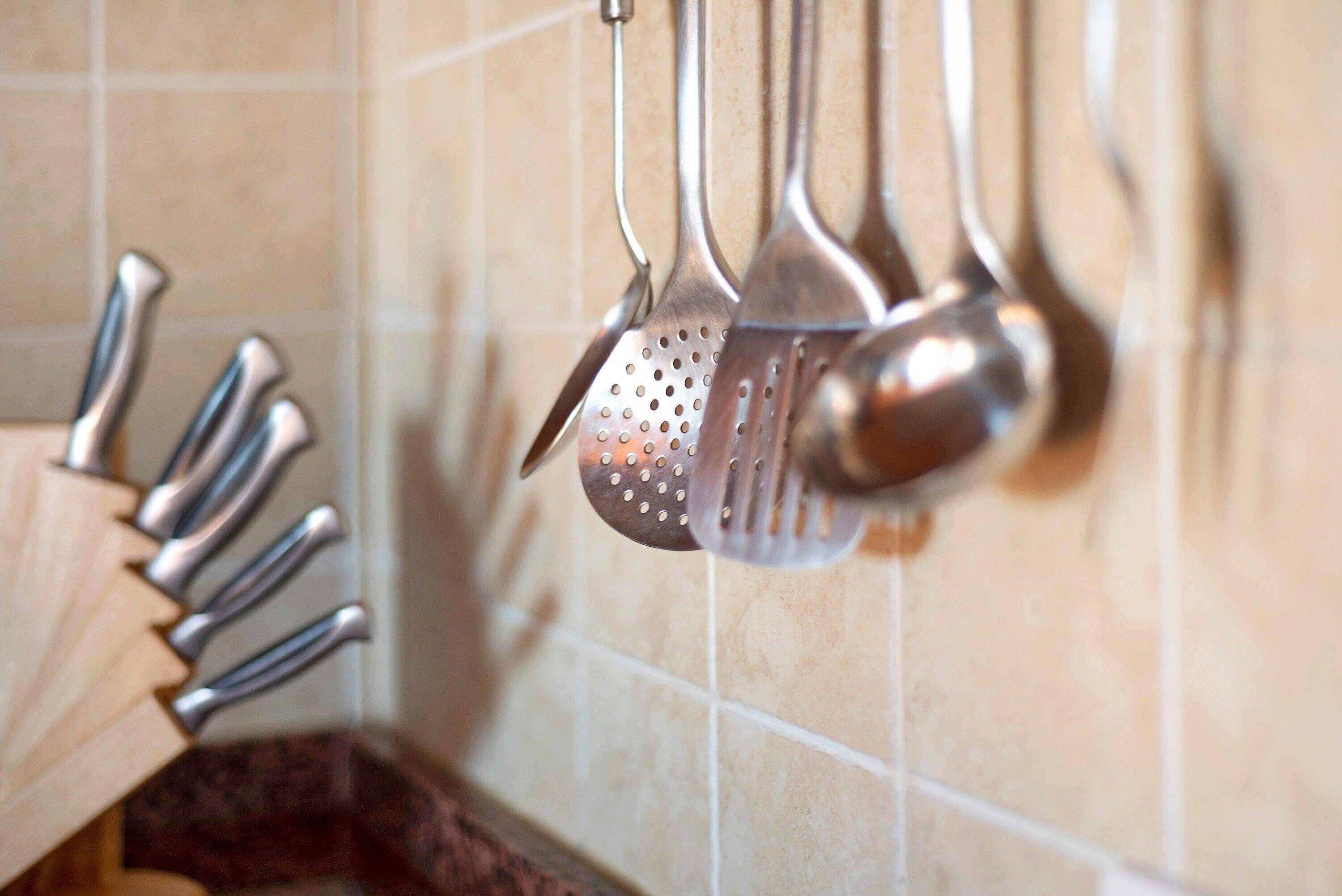 Een keuken met hangende keukengerei en een houten snijplank.