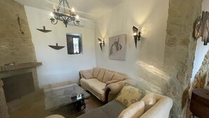 Een woonkamer met een bank, een glazen salontafel, een open haard en kunstwerken aan de muur.