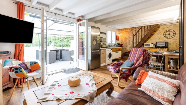 A modern living room with a sofa, a coffee table, a TV, and a dining area with a table and chairs. - Vacation Home "Gite Senguinous 1" with Shared Pool, Private Terrace & Wi-Fi (Lesparre-Médoc)