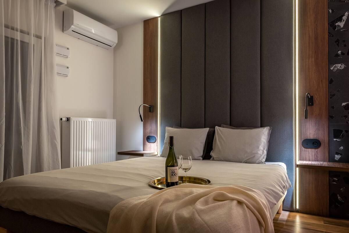 Een moderne hotelkamer met een groot bed, een nachtkastje, een airconditioner en een wandlamp.