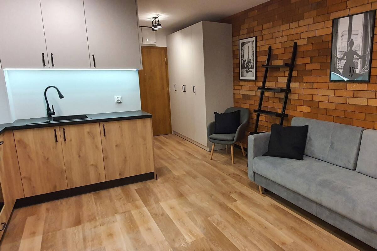 Een moderne keuken met houten kastjes en een grijze bank.