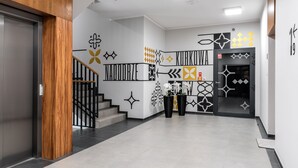Un vestíbul modern amb una escala, motius decoratius a la paret i una zona de recepció.