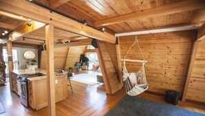 A cozy cabin with a kitchen, dining area, and a hanging chair. - Luxurious Bayview Treehouse: Hot Tub, 15 min to SF (Brisbane)