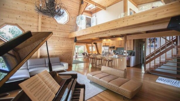 A spacious living area with a grand piano, a sofa, and a staircase leading to an upper level. - Luxurious Bayview Treehouse: Hot Tub, 15 min to SF (Brisbane)