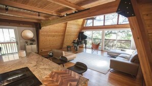 A modern kitchen with a herringbone countertop, a built-in stove, and a dining area with a piano. - Luxurious Bayview Treehouse: Hot Tub, 15 min to SF (Brisbane)