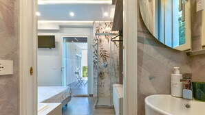 A modern bathroom with a large sink, a mirror, and a shower area. - Villa Serena vista mare (Lacona)