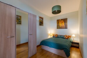 A bedroom with a bed, bedside tables, a wardrobe, and artwork on the walls. - Apartment '2p au Belvédère' with Lake view and Balcony (Thonon-les-Bains)