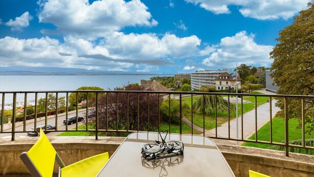Un balcón con mesa, sillas y vista al mar y edificios.