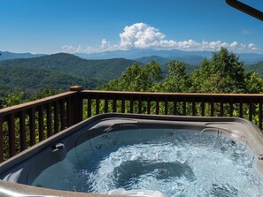 Un bain à remous avec une terrasse en bois et une vue imprenable sur les montagnes.