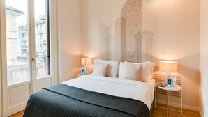 Une chambre d’hôtel avec un lit, deux tables de chevet, une fenêtre et une vue sur les bâtiments environnants.