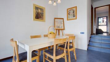 A dining area with a white table, wooden chairs, and framed artwork on the walls.