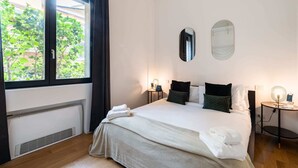 Ein Hotelzimmer mit Bett, Nachttischen, einem Heizgerät und einem Fenster mit Vorhängen.