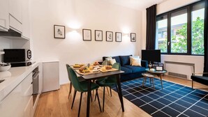 Ein modernes, kompaktes Wohnzimmer mit Essbereich, Küchenzeile und einer Couch.