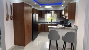 Una cocina moderna con armarios de madera, un refrigerador negro y una encimera de granito.