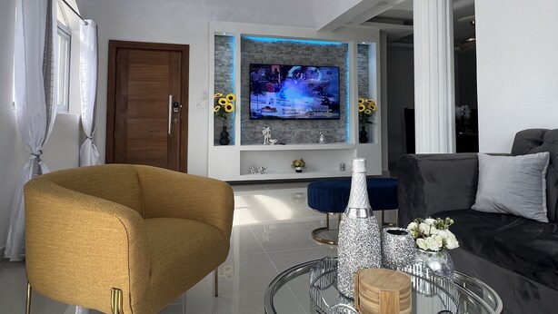 Una sala de estar moderna con un televisor de pantalla plana, un sofá cómodo, un sillón elegante y una mesa de centro de vidrio.