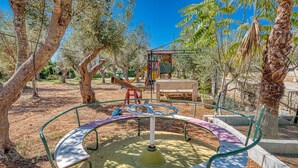 Ein Spielplatz mit Karussell, Schaukeln und einer Kletterkonstruktion.