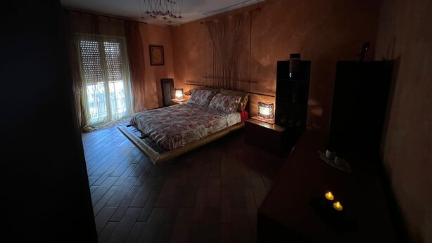 A bedroom with a bed, bedside tables, a wardrobe, and a ceiling fan. - Apartment With Terrace Close to Catania, Sicily (Adrano)