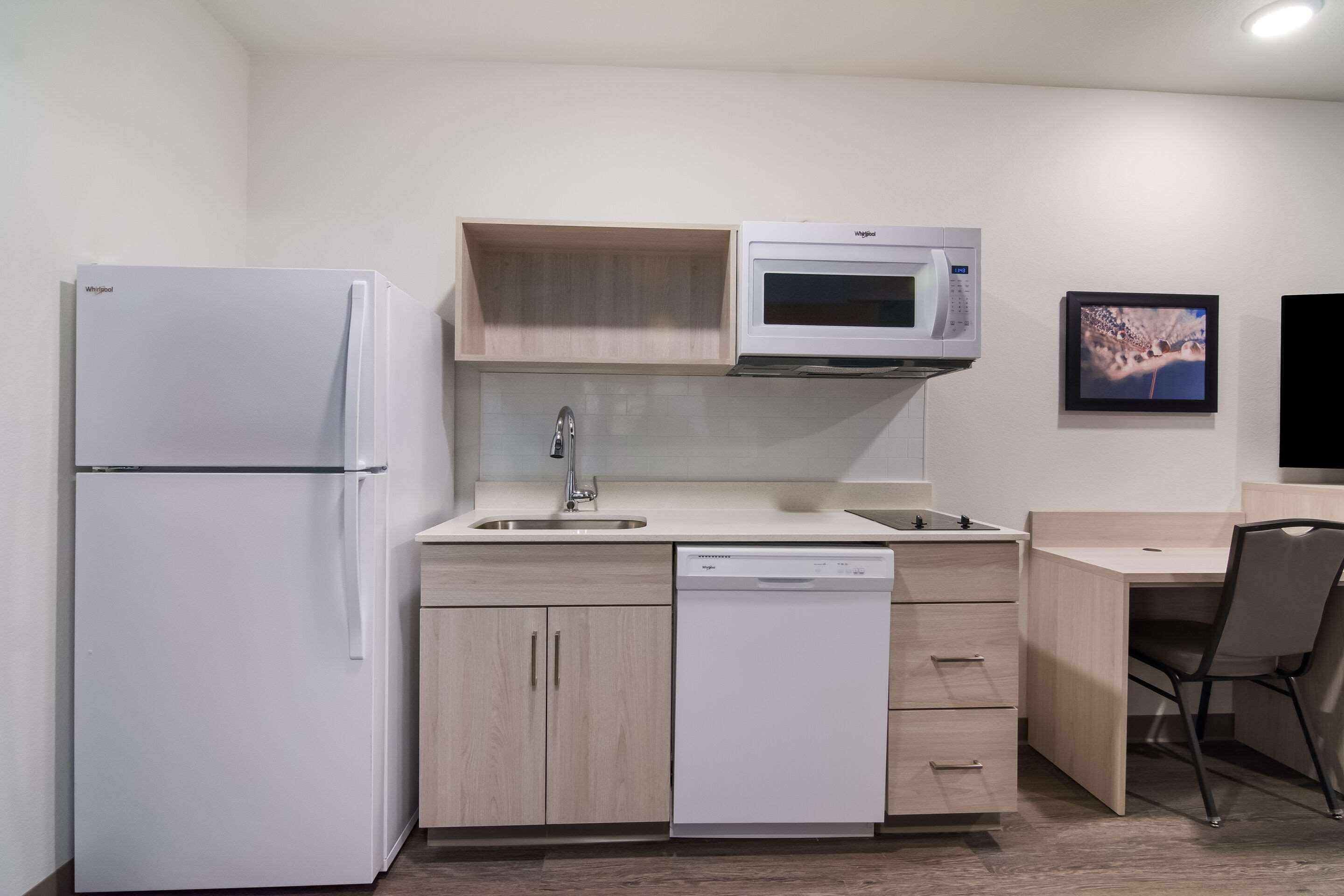 Uma cozinha compacta equipada com frigorífico, micro-ondas, pia e máquina de lavar louça.