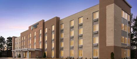 A multi-story hotel with a brick facade, large windows, and a covered entrance area.