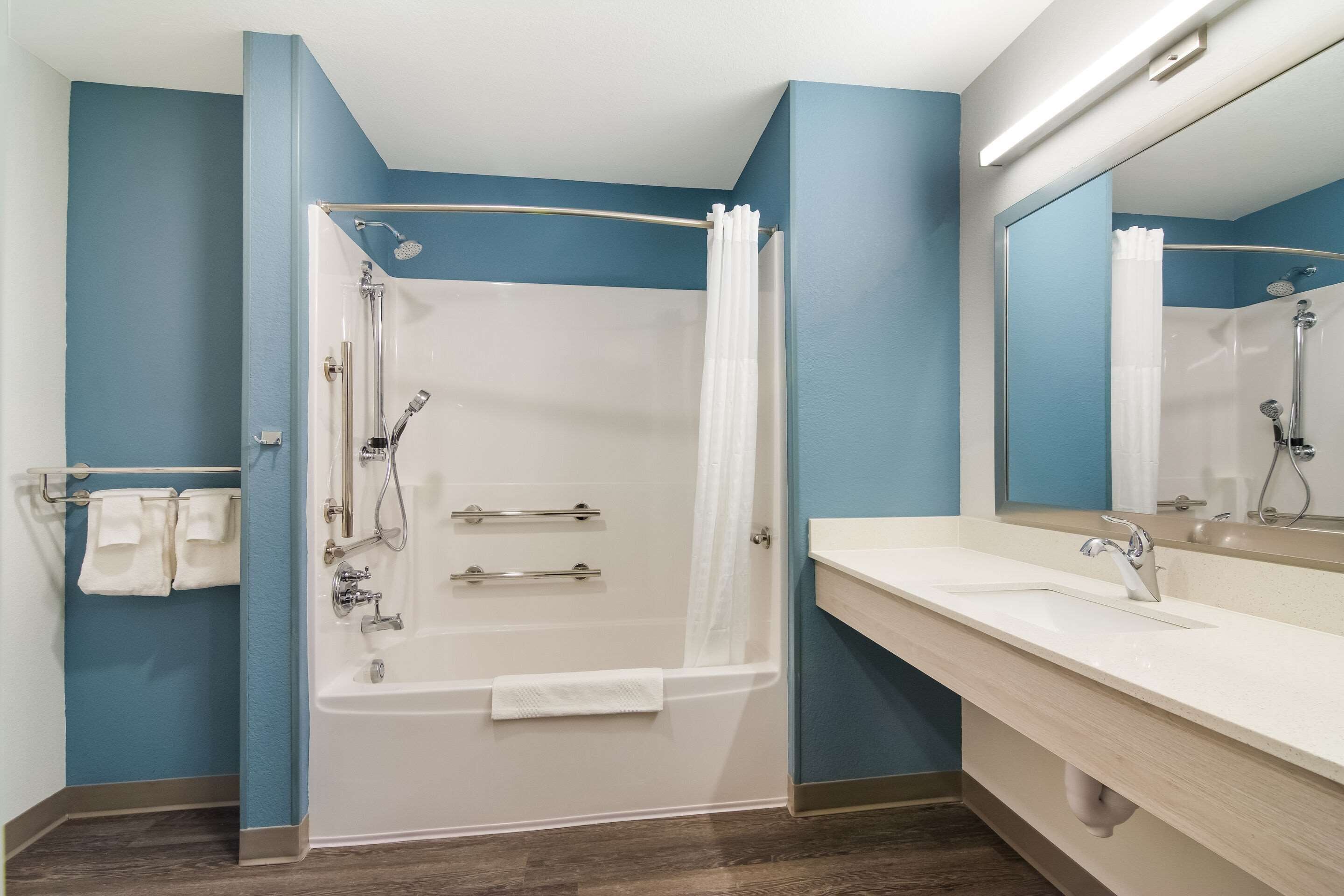 A modern bathroom with a bathtub, shower, and vanity.
