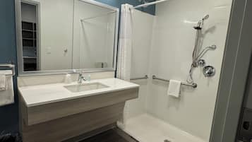 Un baño moderno con lavamanos doble, cabina de ducha de vidrio y rejilla de ventilación en el techo.