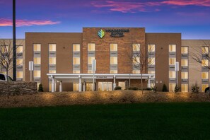 Un hôtel à la façade en briques, doté de nombreuses fenêtres et d’une enseigne indiquant « Woodspring Suites ».