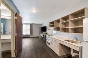 Una cocina moderna con armarios de madera, un lavamanos empotrado y un televisor de pantalla plana.