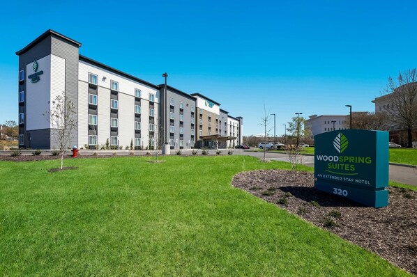 Un hotel de varios pisos con un cartel que indica 'Woodspring Suites' y 'Un Hotel para Estancias Largas'.