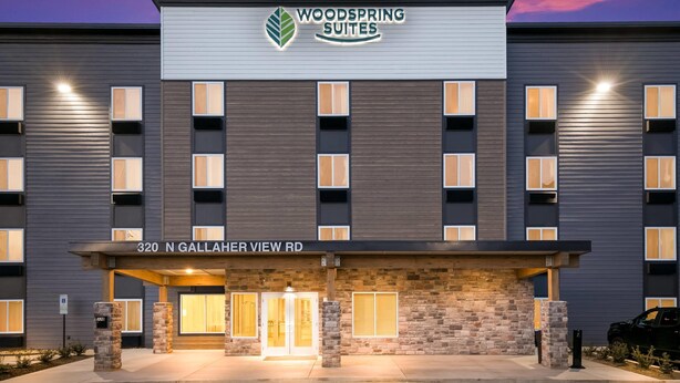A hotel with a modern facade, a sign reading "Woodspring Suites," and the address "320 N Gallaher View Rd." - WoodSpring Suites Knoxville West (Knoxville)