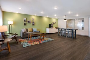 Een moderne woonkamer met een bank, salontafel en een eethoek met stoelen.