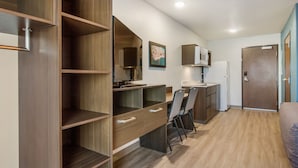 A compact kitchen with wooden cabinets, a microwave, and a refrigerator. - WoodSpring Suites Knoxville West (Knoxville)