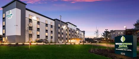 A modern hotel building with a sign indicating it's a Woodspring Suites extended stay hotel.