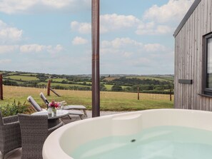 A hot tub with a view of rolling hills and a wooden building. - The Pennymoor (Tiverton)