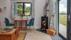 A cozy room with a dining table, chairs, a fireplace, and a view of the outdoors. - The Pennymoor (Tiverton)