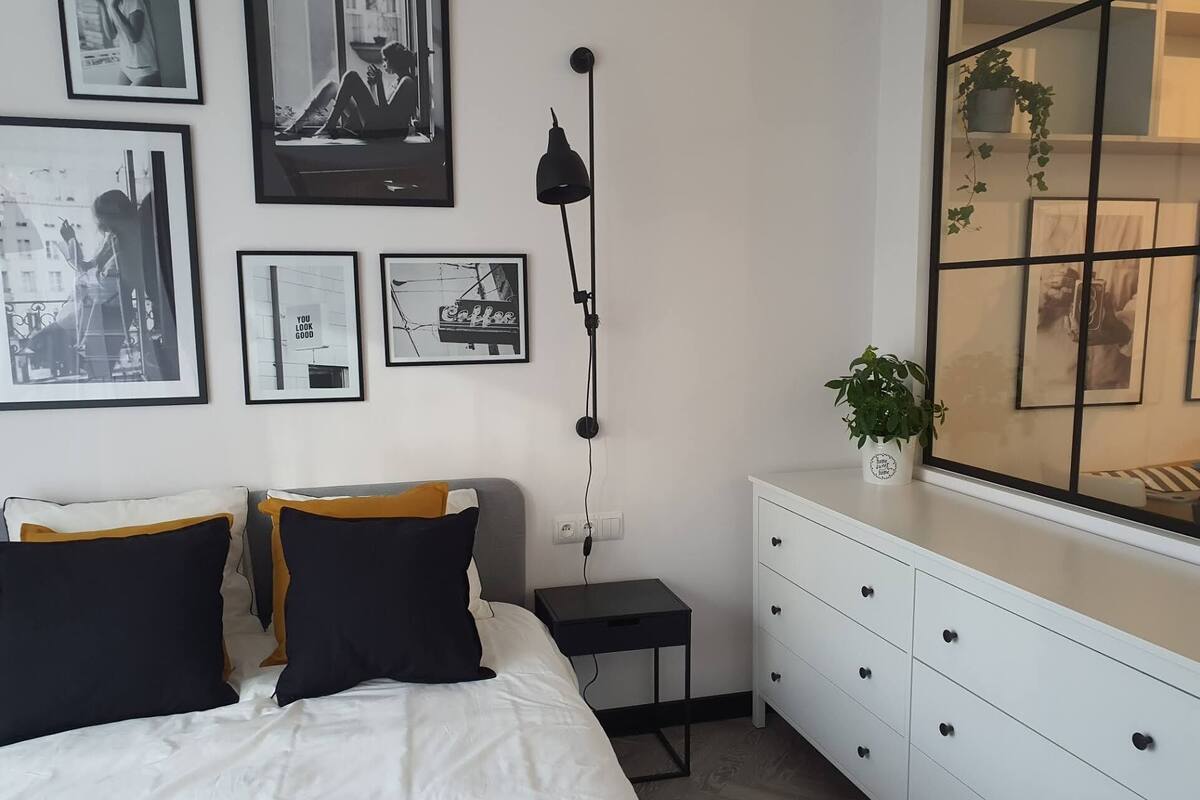 A bedroom with a bed, bedside tables, a dresser, and framed pictures on the wall.