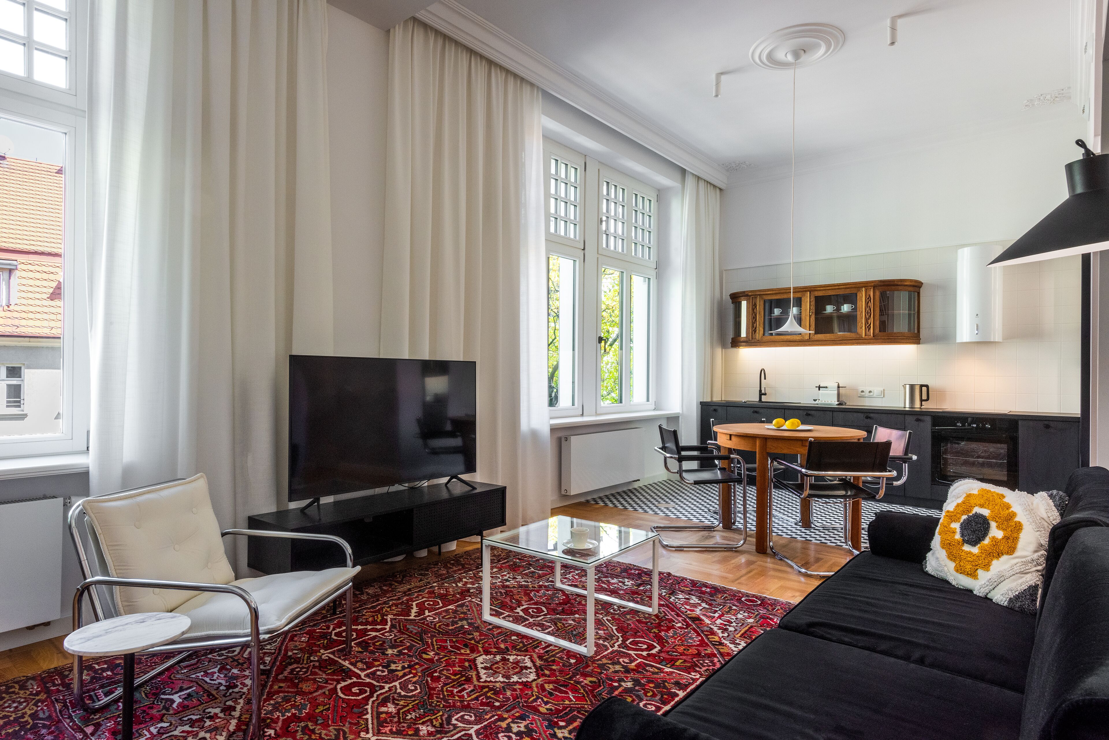 A modern living room with a sofa, a glass coffee table, a TV, and a dining area with a table and chairs.