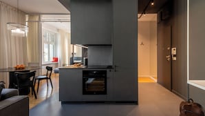 Una cucina moderna con elettrodomestici integrati, una zona pranzo con tavolo e sedie, e un corridoio che conduce a una camera da letto.