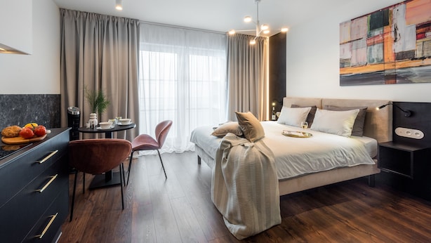 Una camera d'albergo moderna con un letto, un comodino e un'area pranzo con una sedia e un tavolo.
