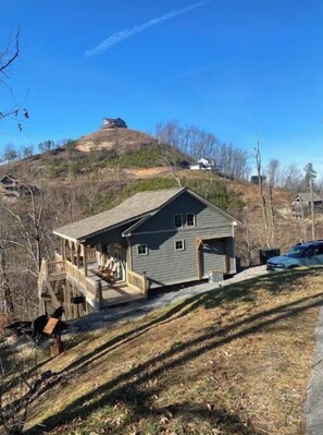 Stunning home with a gabled roof and front porch, set on a sloped terrain.