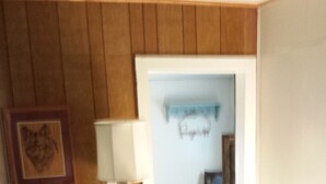 A beige sofa with a wooden base, a patterned rug, and a framed picture on the wall.
