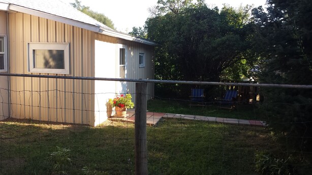 A house with a fenced yard, a wooden deck, and a small garden with flowers.