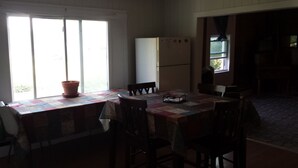 A kitchen with a table and chairs, a refrigerator, and a window with curtains.