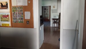 A hallway with a bulletin board, a refrigerator, and a microwave.